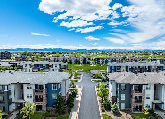A road runs through a residential area with apartment buildings on either side.