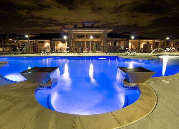 A large outdoor swimming pool with a spa and a building in the background.