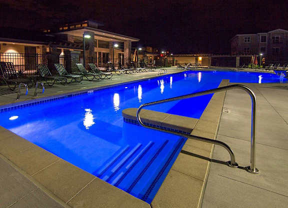 A swimming pool at night with a metal ladder.
