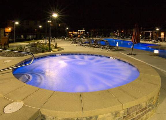 A round swimming pool surrounded by a stone wall at night.
