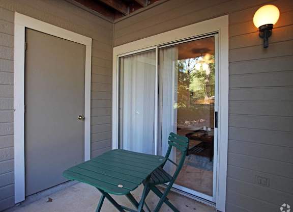 A green chair is placed on a porch.