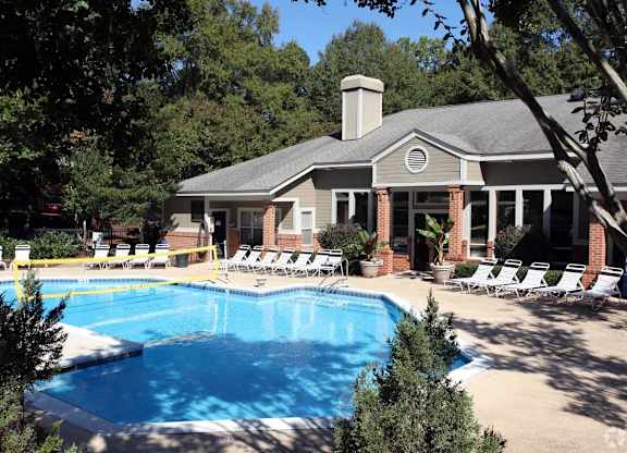 A pool in front of a house with a sun lounger.