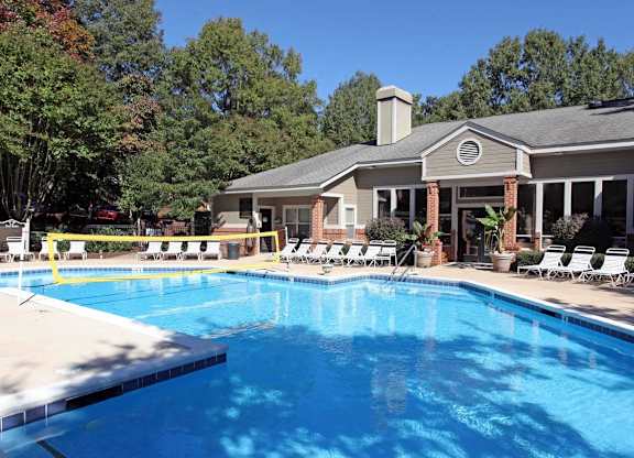 A pool with a yellow fence and a house in the background.