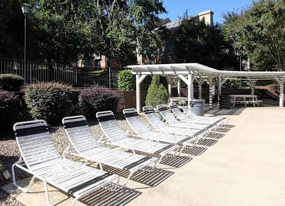 A row of sun loungers are arranged on a patio.