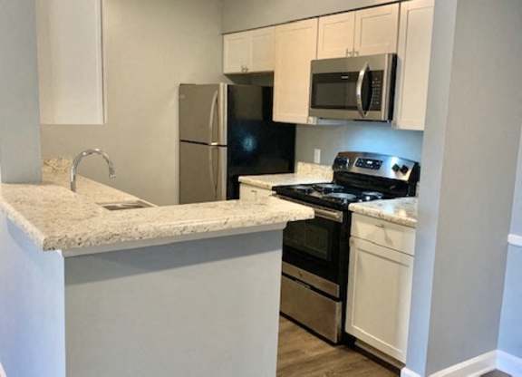 A kitchen with a refrigerator, oven, and microwave.