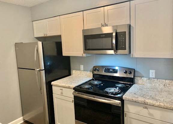 A kitchen with a black stove top oven and a black microwave above it.