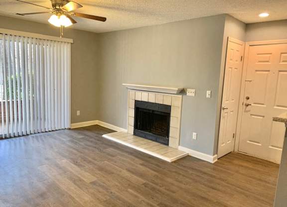 A living room with a fireplace and a ceiling fan.
