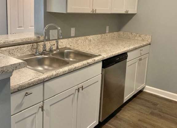 A kitchen with white cabinets and a marble countertop.