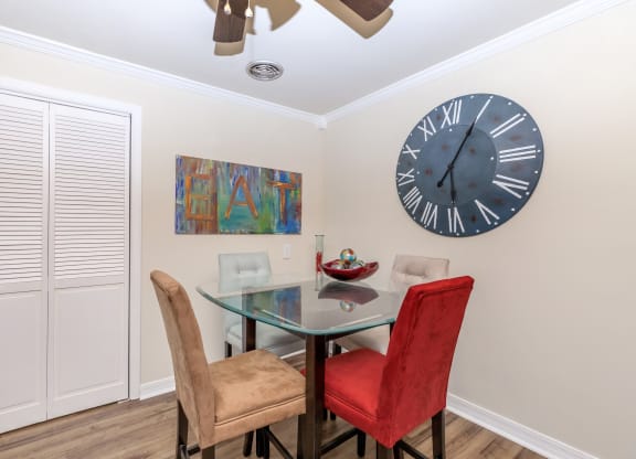 a dining room with a glass table and chairs and a large clock on the wall
