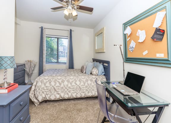 a bedroom with a bed and a desk with a laptop