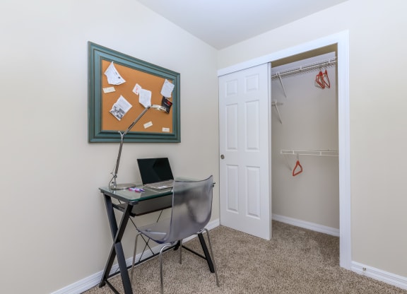 a small desk with a laptop and a lamp in the corner of a room with a closet