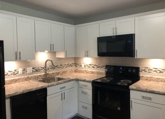 a kitchen with white cabinets and black appliances