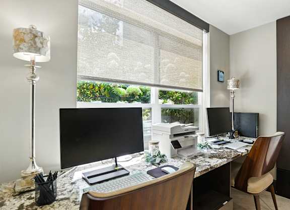 A modern home office with a large window and two monitors at Alinea Town and Country Luxury Apartments in Des Peres MO 63131.