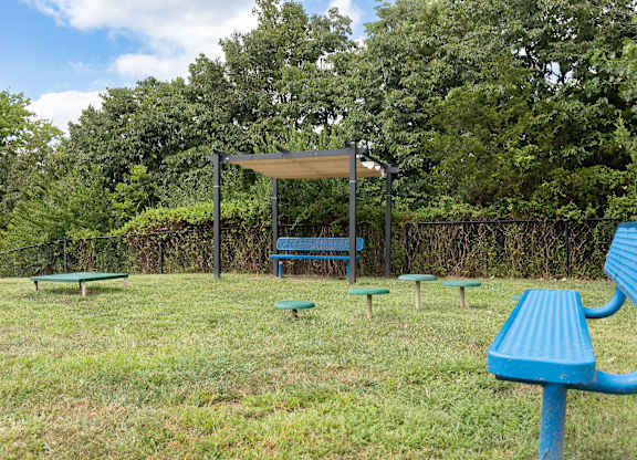 A park with a blue bench and picnic table at Alinea Town and Country Luxury Apartments in Des Peres MO 63131.