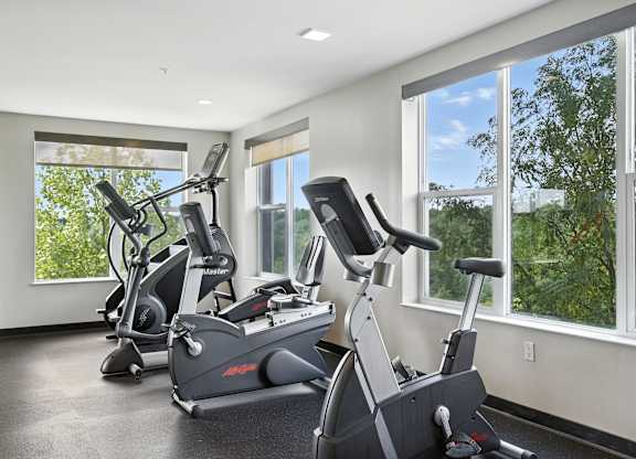 A room with a treadmill, a stationary bike, and a rowing machine at Alinea Town and Country Luxury Apartments in Des Peres MO 63131.