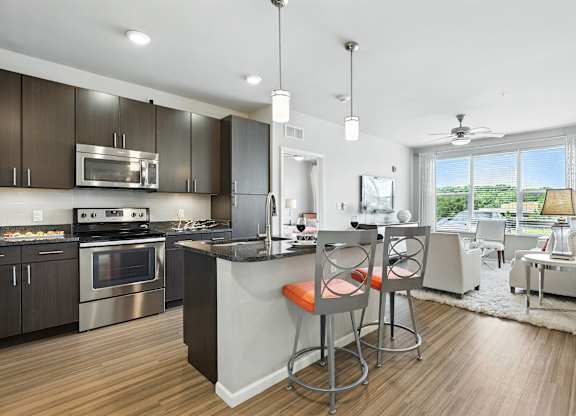 A modern kitchen with a bar stool and a dining table at Alinea Town and Country Luxury Apartments in Des Peres MO 63131.