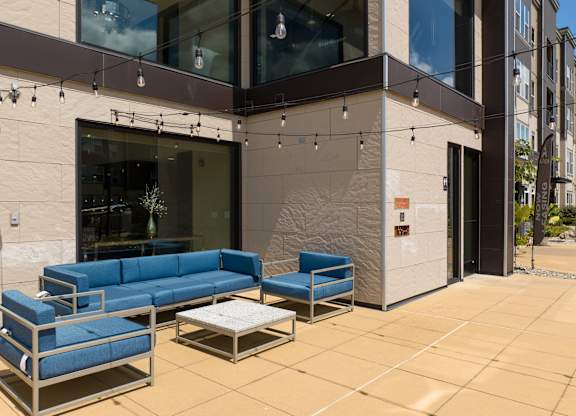 A patio with a blue couch and a table at Alinea Town and Country Luxury Apartments in Des Peres MO 63131..