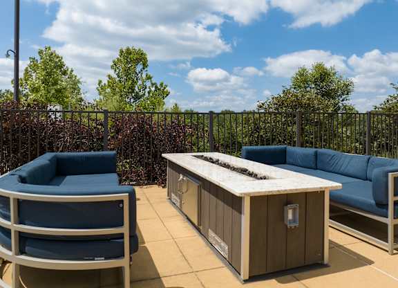 A blue couch and a wooden table are on a patio at Alinea Town and Country Luxury Apartments in Des Peres MO 63131..