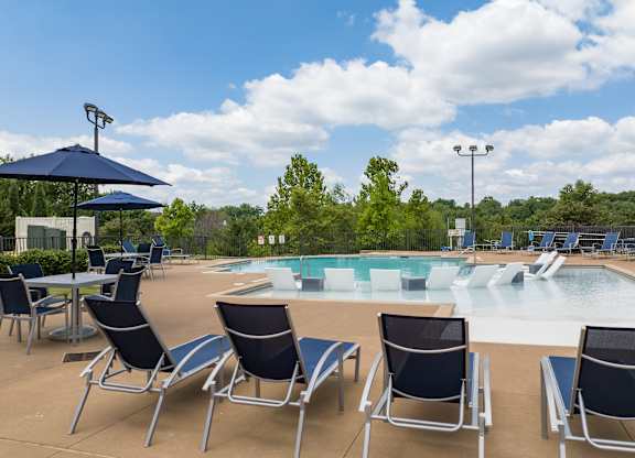 A pool area with chairs and umbrellas at Alinea Town and Country Luxury Apartments in Des Peres MO 63131.