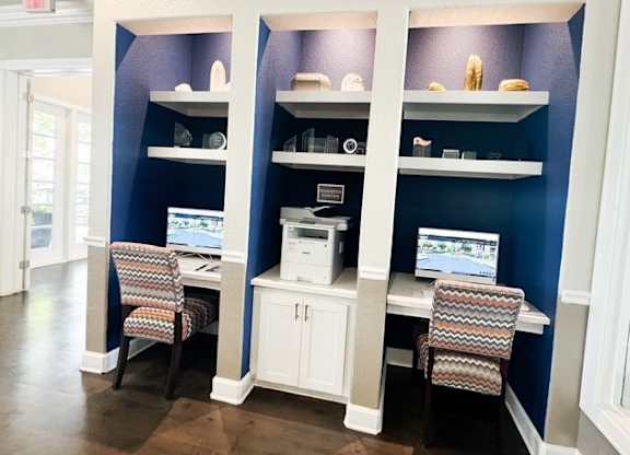 A room with a blue wall and a desk with a computer and printer.