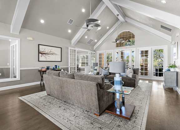 A living room with a grey couch and a glass coffee table.