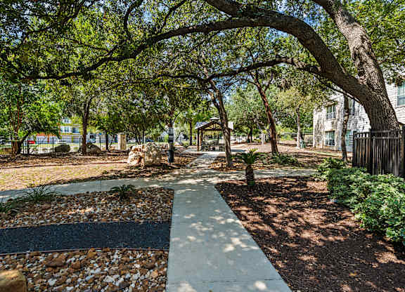 A walkway in a park with trees on either side.