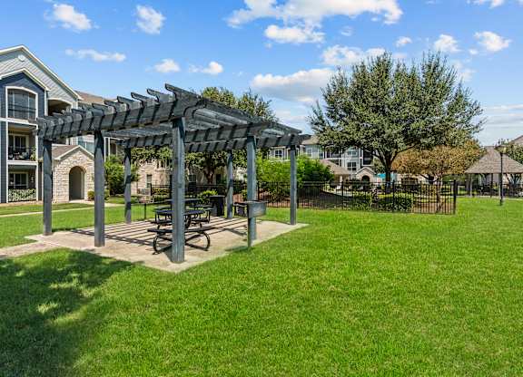 A park with a picnic table and a pergola.