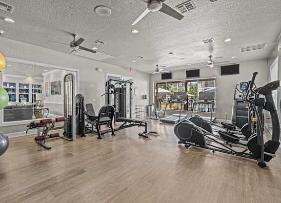 A gym with a variety of equipment including a treadmill, weights, and a bench press.