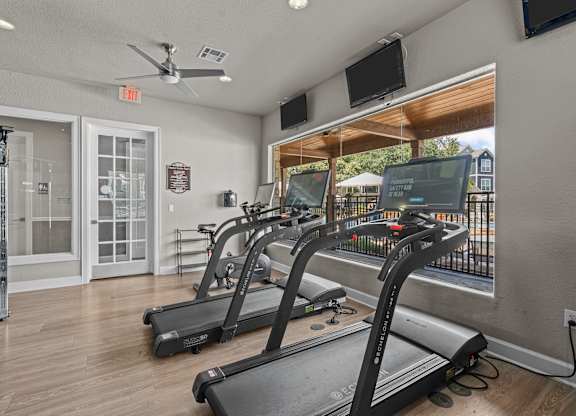 A gym with treadmills and a fan.