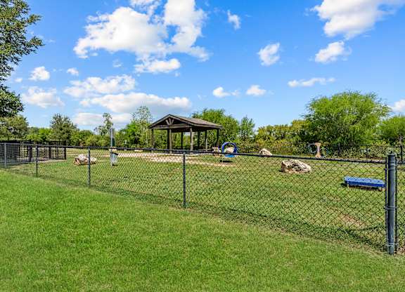 A park with a gazebo, a playground, and a fence.