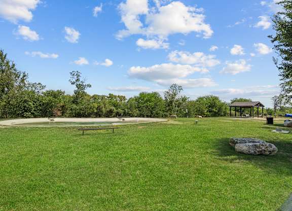 A park with a grassy field and a pavilion in the distance.