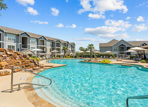 A large swimming pool in front of a resort-style building.