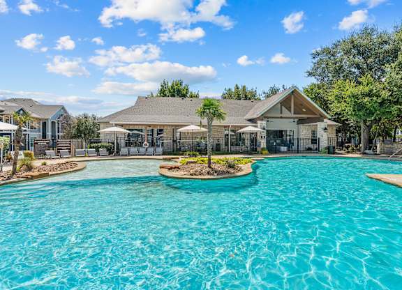 A large swimming pool with a house in the background.