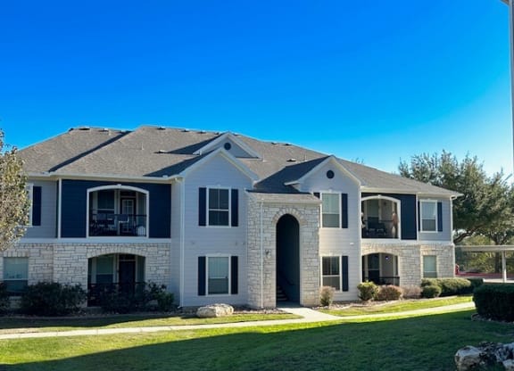 a large white house with a yard and a blue sky