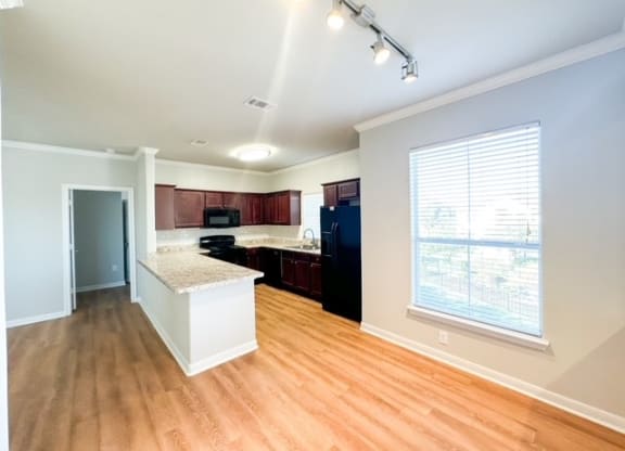 an empty kitchen with wood floors and a large window