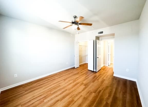 an empty living room with a ceiling fan and wood floors