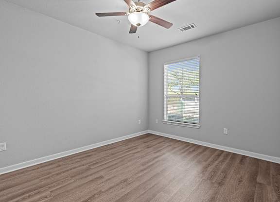 A room with a ceiling fan and a window with blinds.
