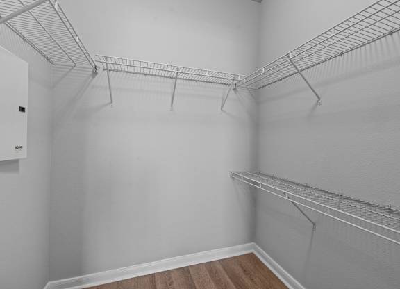 A white walk in closet with shelves and a door.