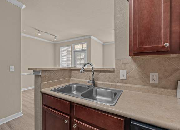 A kitchen with a sink and brown cabinets.