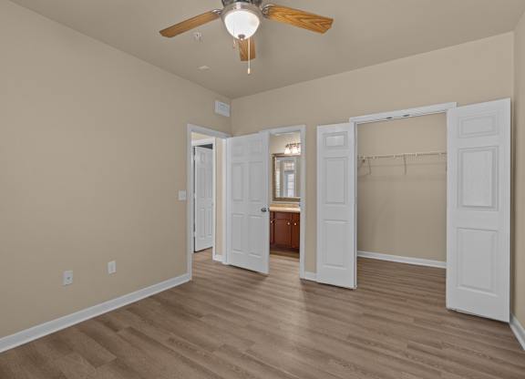 A room with a ceiling fan and wooden flooring.