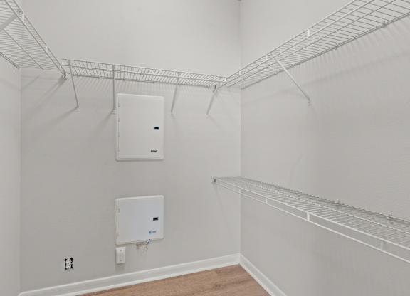 A white closet with a white door and a white electrical box on the wall.