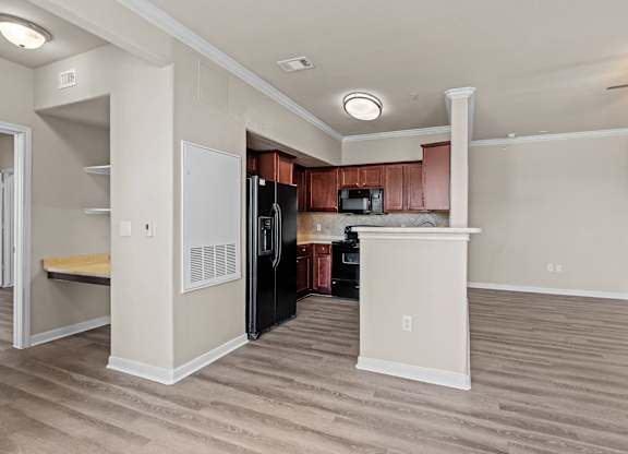 A kitchen with a black refrigerator and wooden cabinets.