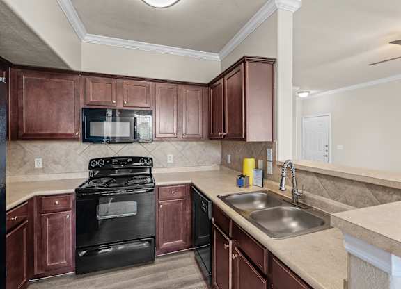 A kitchen with brown cabinets and a black stove top oven.