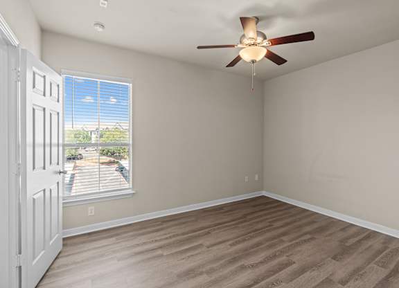 A room with a ceiling fan and a window with blinds.