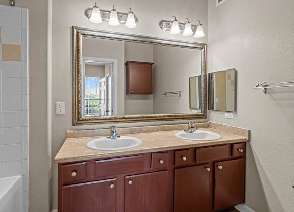 A bathroom with a sink, mirror, and cabinets.