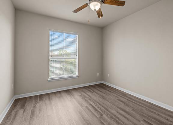 A room with a ceiling fan and a window with blinds.