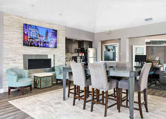 A modern dining room with a large TV mounted above the fireplace at Bramblett Hills Luxury Apartments in O Fallon MO 63366