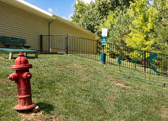 A red fire hydrant is in the foreground of a grassy area at Bramblett Hills Luxury Apartments in O Fallon MO 63366