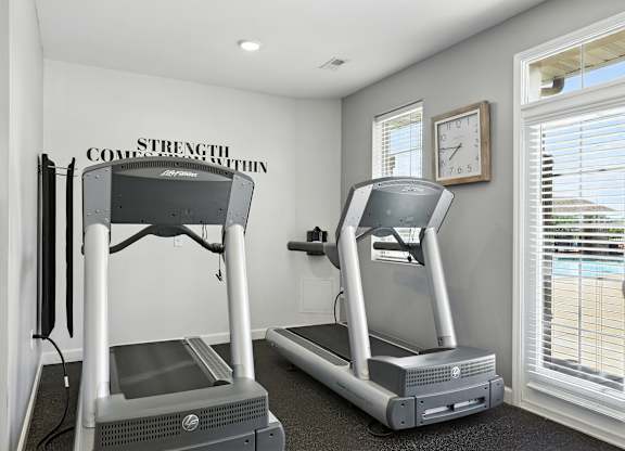 Two treadmills are placed in a room with a wall that says