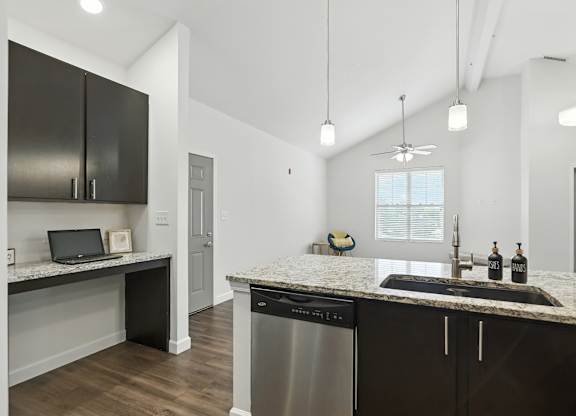 A modern kitchen with dark brown cabinets and a granite countertop at Bramblett Hills Luxury Apartments in O Fallon MO 63366